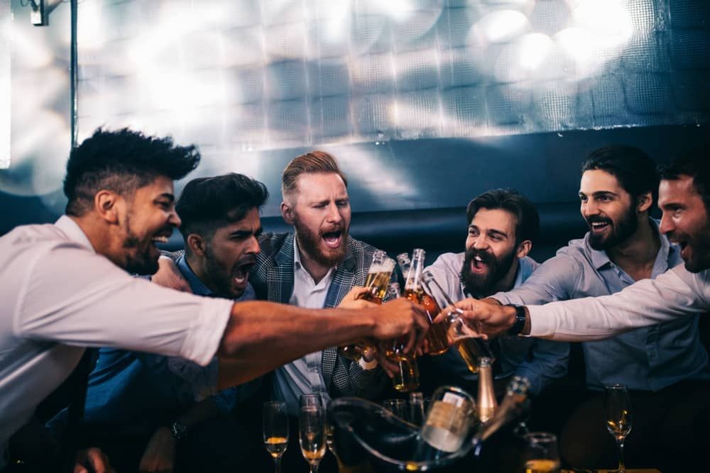 Friends raising drinks at a Las Vegas strip club crawl, enjoying VIP services and private access, tailored for Texas guests.